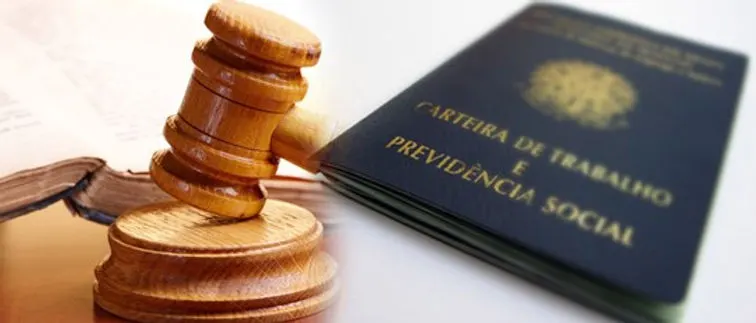 Carteira de Trabalho e Previdência Social sobre um livro, ao lado de um martelo de juiz